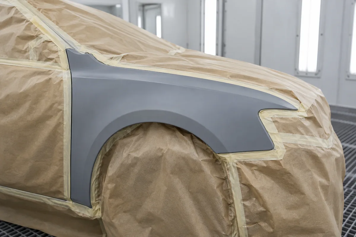 Aile de voiture recouverte d&rsquo;apprêt gris mat avec papier de masquage sur les parties voisines