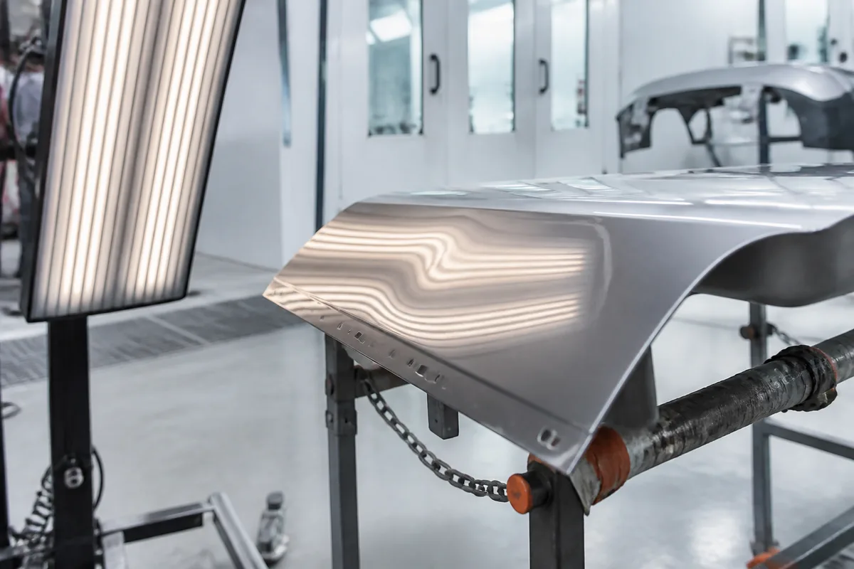 Reflet de lignes lumineuses sur une carrosserie révélant une déformation