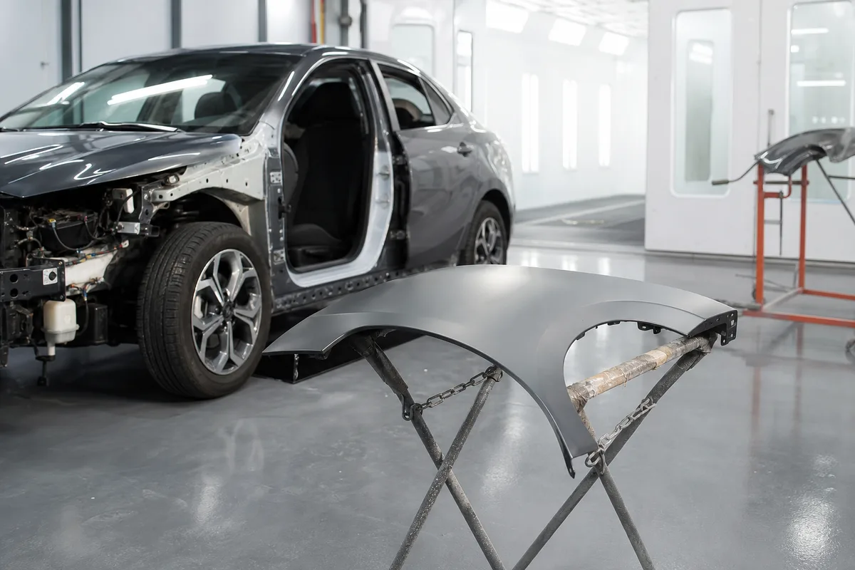 Véhicule stationné dans un atelier avec éléments de carrosserie démontés