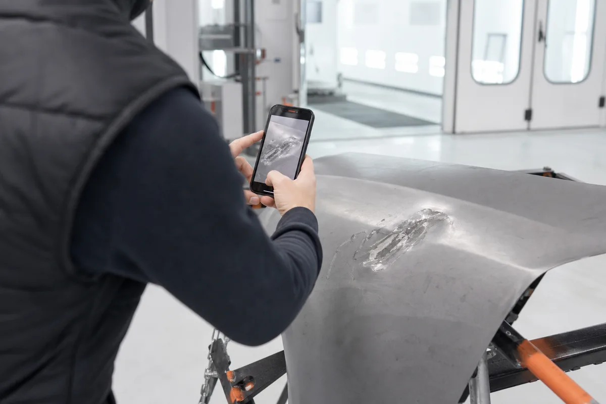 Automobiliste photographiant un dommage de carrosserie avec un téléphone